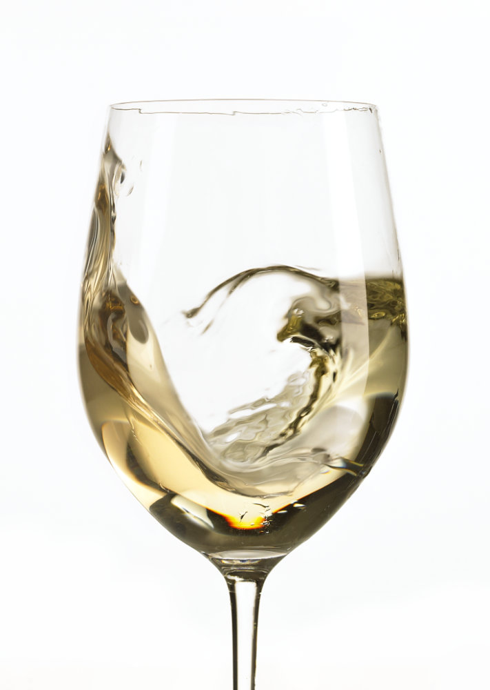 Action shot of white wine swirled in wine glass – Photograph by George Ong